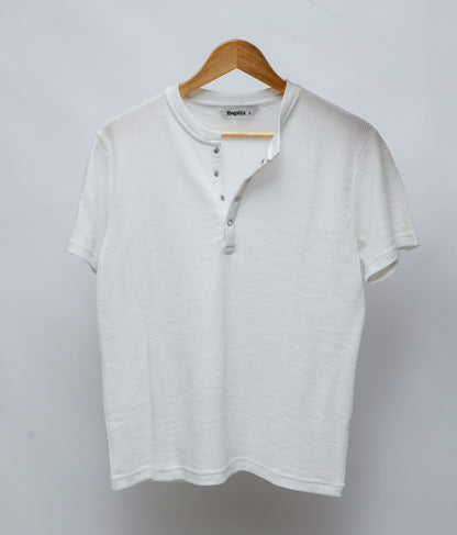 A white short-sleeve Henley T-shirt with a ribbed collar with four clip on button placket, hanging on a wooden hanger against a light gray background.
