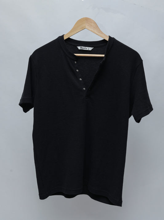 A Black short-sleeve Henley T-shirt with a ribbed collar and four-button placket, hanging on a wooden hanger against a light gray background.