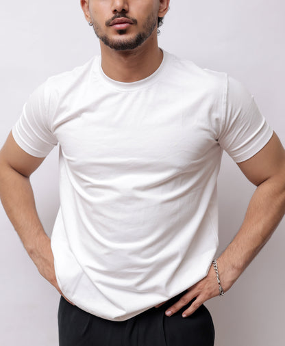 A man wearing a white short-sleeve crewneck t-shirt and black pants, shown from a high-angle perspective against a plain light gray background.